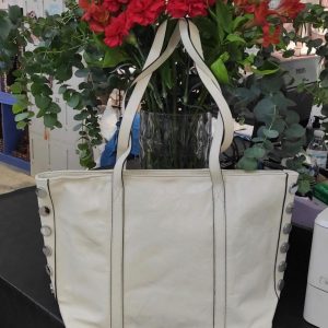 Bolso shopper de piel en color crudo con detalles de tachuelas plateadas en los laterales.